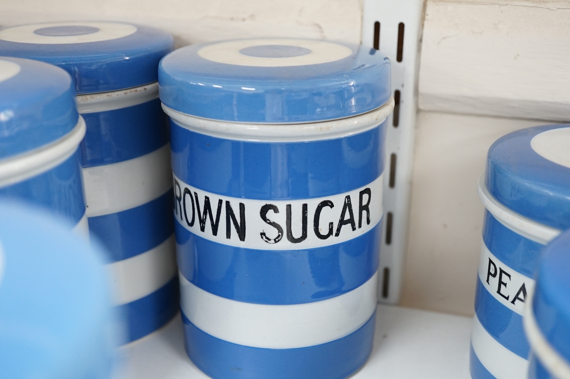 T.G.Green Cornish Kitchenware, nine 14cm lidded storage jars to include Custard Powder, Sago, Tapioca, Brown Sugar, Bread Crumbs and Prunes, Black Shield marks. Condition - fair to good